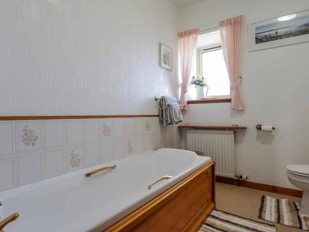 a bathroom with a tub and a toilet at Braehead Croft in Portessie