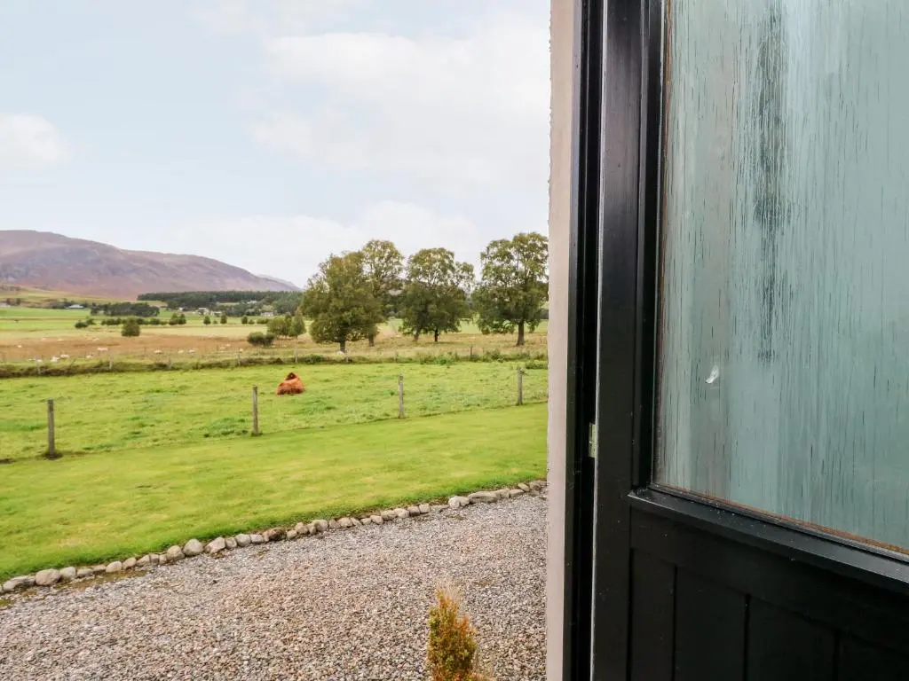 an open door to a field with a horse in the distance at Creag-na-Sanais in Laggan