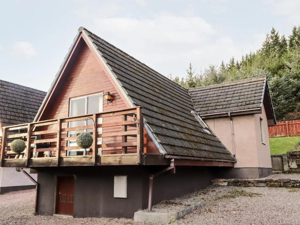 a house with a deck on the side of it at Larchfield Chalet 2 in Auchterneed