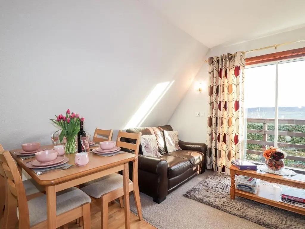 a living room with a table and a couch at Larchfield Chalet 2 in Auchterneed