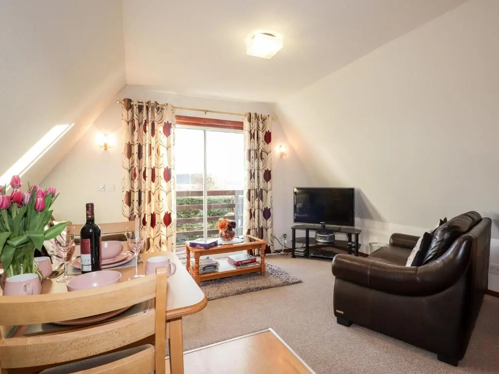 a living room with a couch and a table at Larchfield Chalet 2 in Auchterneed