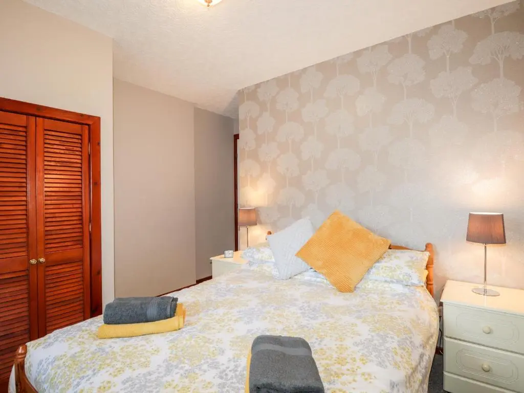 a small bedroom with a bed and a chair at Larchfield Chalet 2 in Auchterneed
