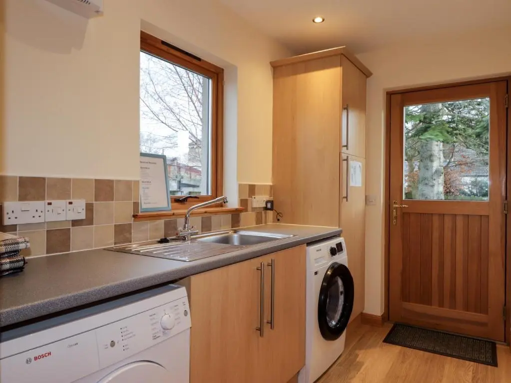 a kitchen with a sink and a washing machine at Bruach Gorm Cottage in Grantown on Spey