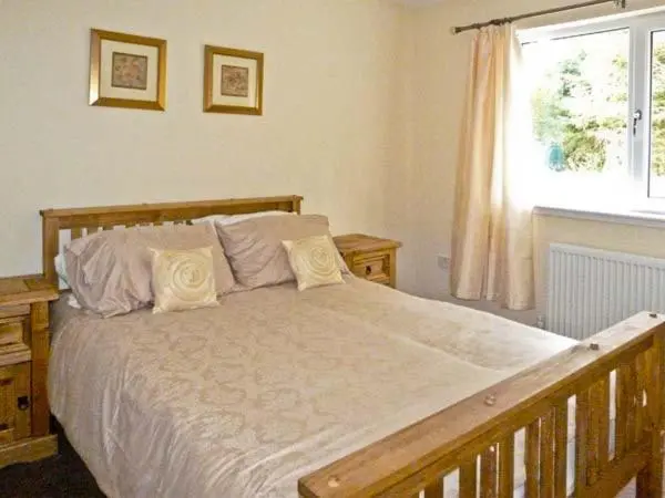 a bedroom with a large white bed with a window at Braewood in Invermoriston
