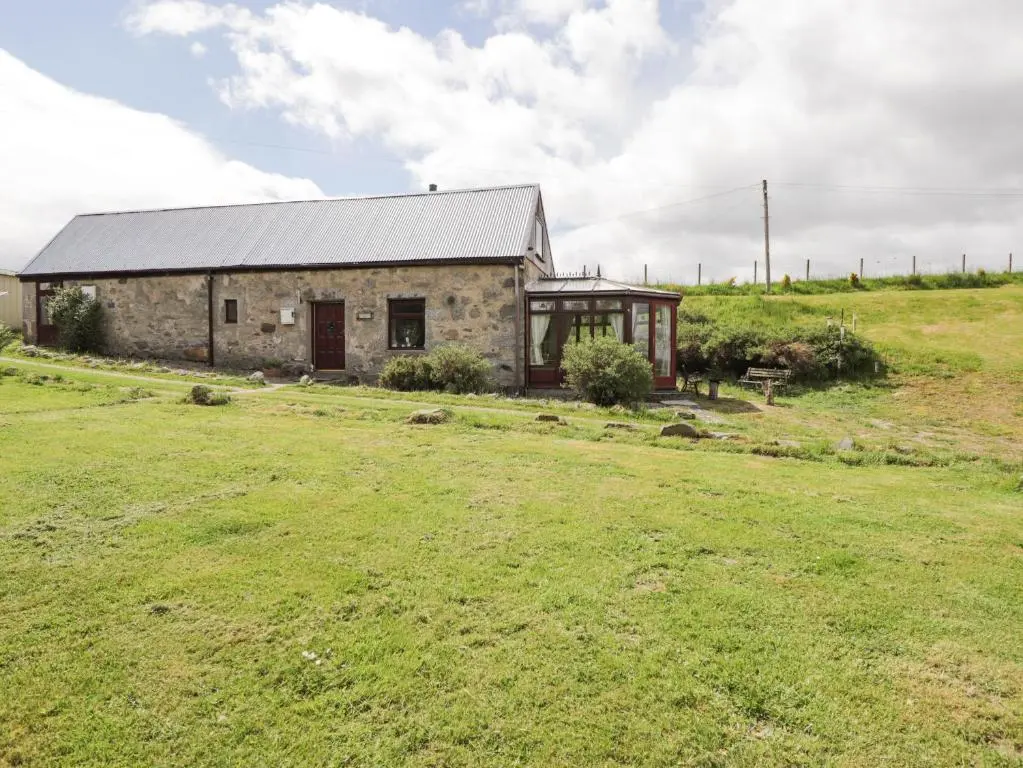 a stone building with a grass field in front of it at Blairgorm Croft in Nethy Bridge