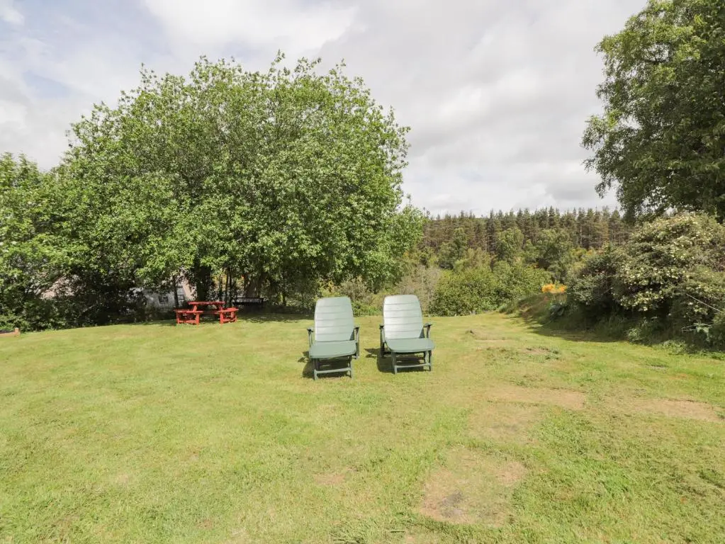 two chairs sitting in the grass in a field at Blairgorm Croft in Nethy Bridge