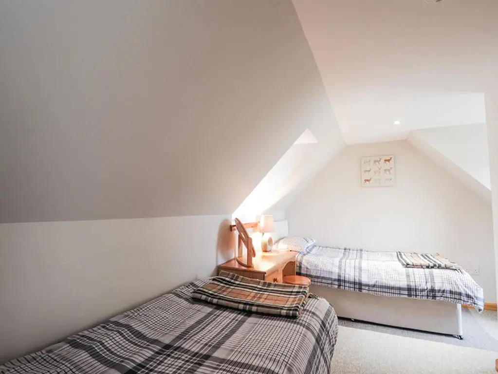 a attic bedroom with two beds and a ladder at The Croft House in Muir of Ord