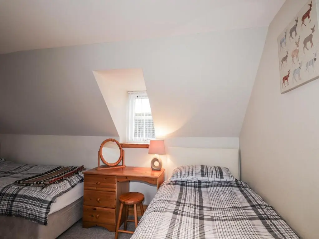 a bedroom with two beds and a desk and a window at The Croft House in Muir of Ord