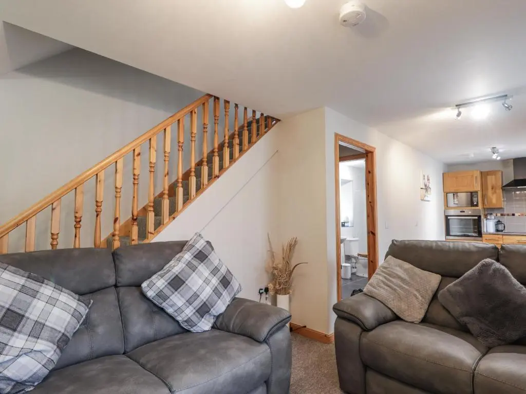 a living room with two couches and a staircase at The Croft House in Muir of Ord