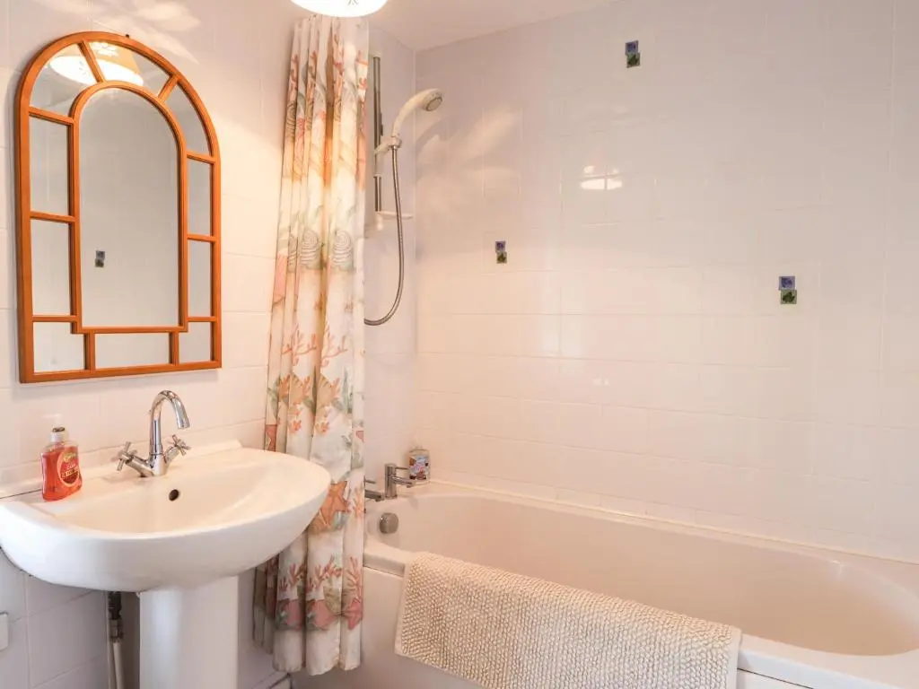 a white bathroom with a sink and a bath tub at Holly Hoose in Findochty