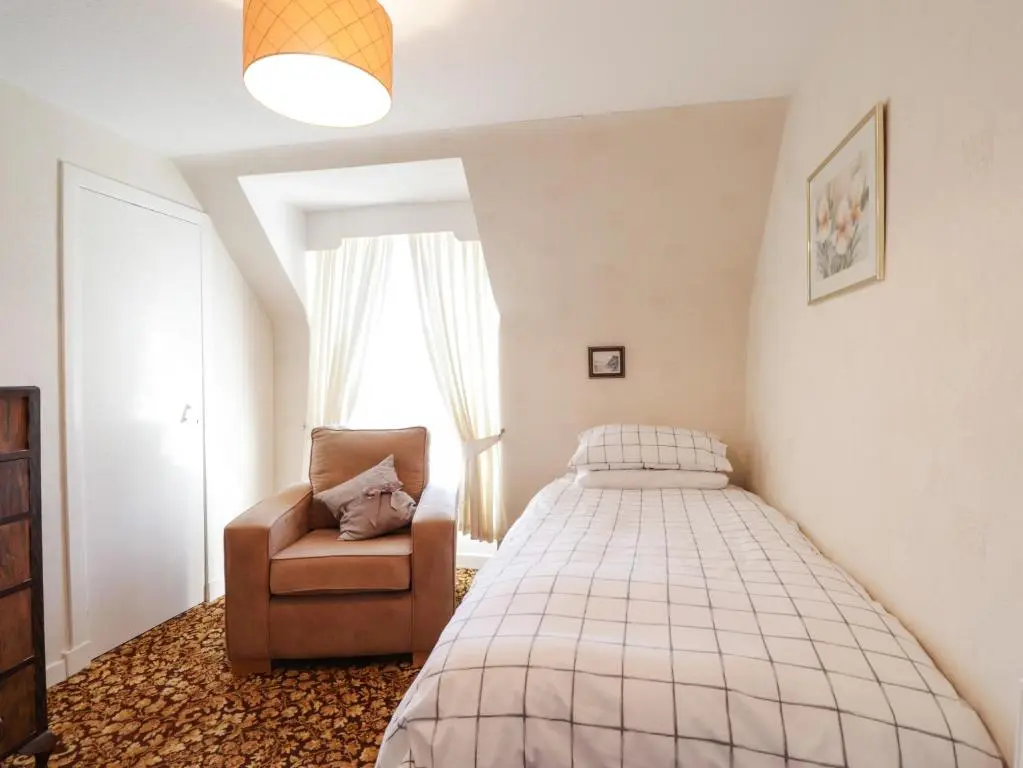 a bedroom with a bed and a chair at Holly Hoose in Findochty