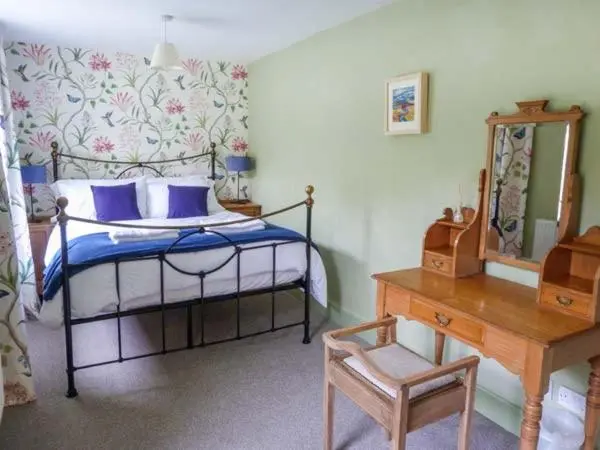 a bedroom with a bed and a table and a chair at Easter Duthil Cottage in Duthil