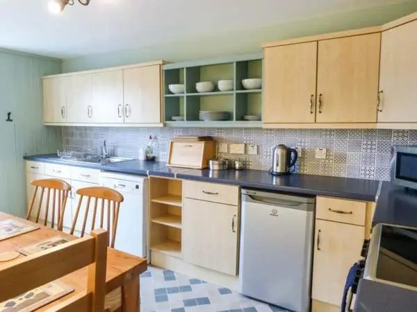 a kitchen with white appliances and wooden cabinets and a table at Easter Duthil Cottage in Duthil