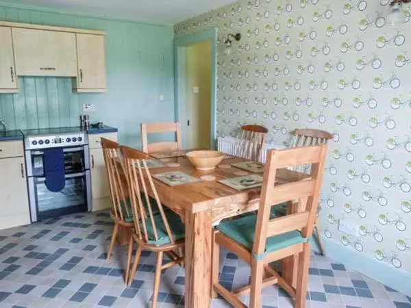 a kitchen with a wooden table and four chairs at Easter Duthil Cottage in Duthil