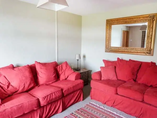 a living room with a red couch and a mirror at Easter Duthil Cottage in Duthil