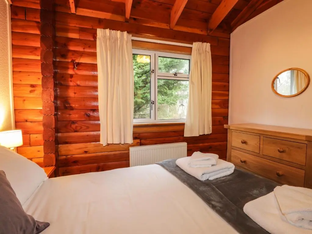 a bedroom with a bed and a window at Spruce Lodge in Strathpeffer