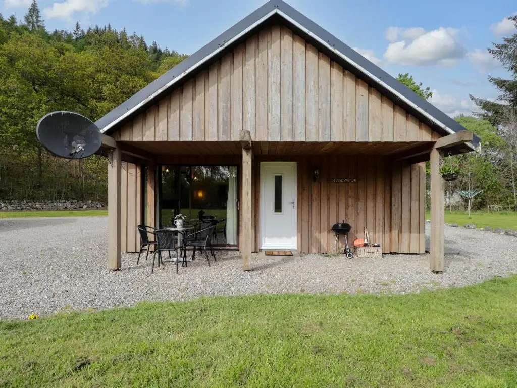 a large wooden building with a table and chairs at Stone Water Cottage in Contin
