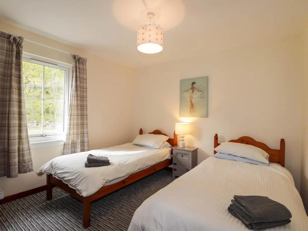 a bedroom with two beds and a window at Pebbles Cottage in Contin