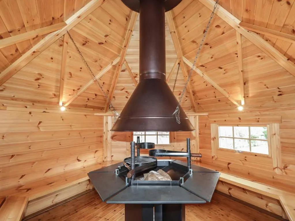 a stove in a log cabin with wooden walls at Little Chestnut in Muir of Ord