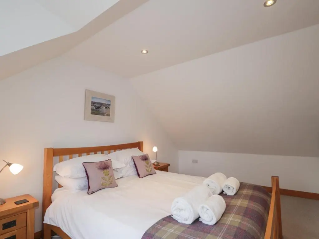 a bedroom with a bed with towels on it at Little Chestnut in Muir of Ord