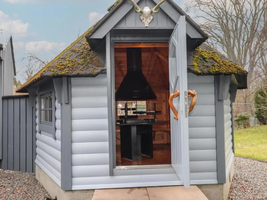 a playhouse with a large window in a garden at Little Chestnut in Muir of Ord