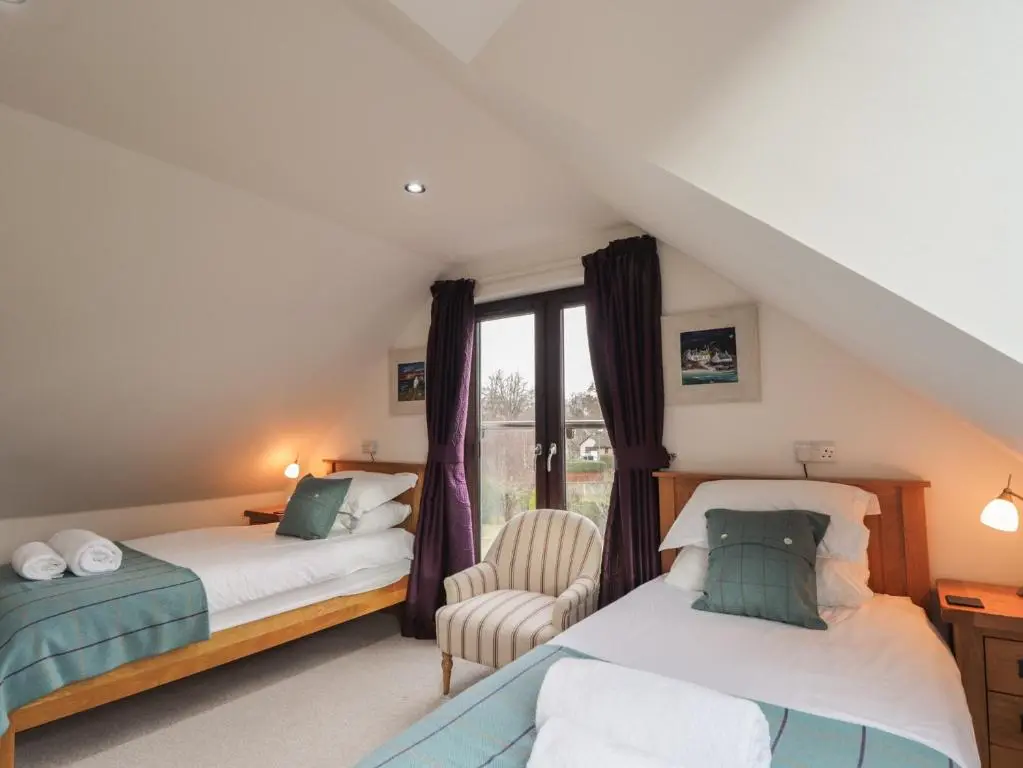 a attic bedroom with two beds and a window at Little Chestnut in Muir of Ord