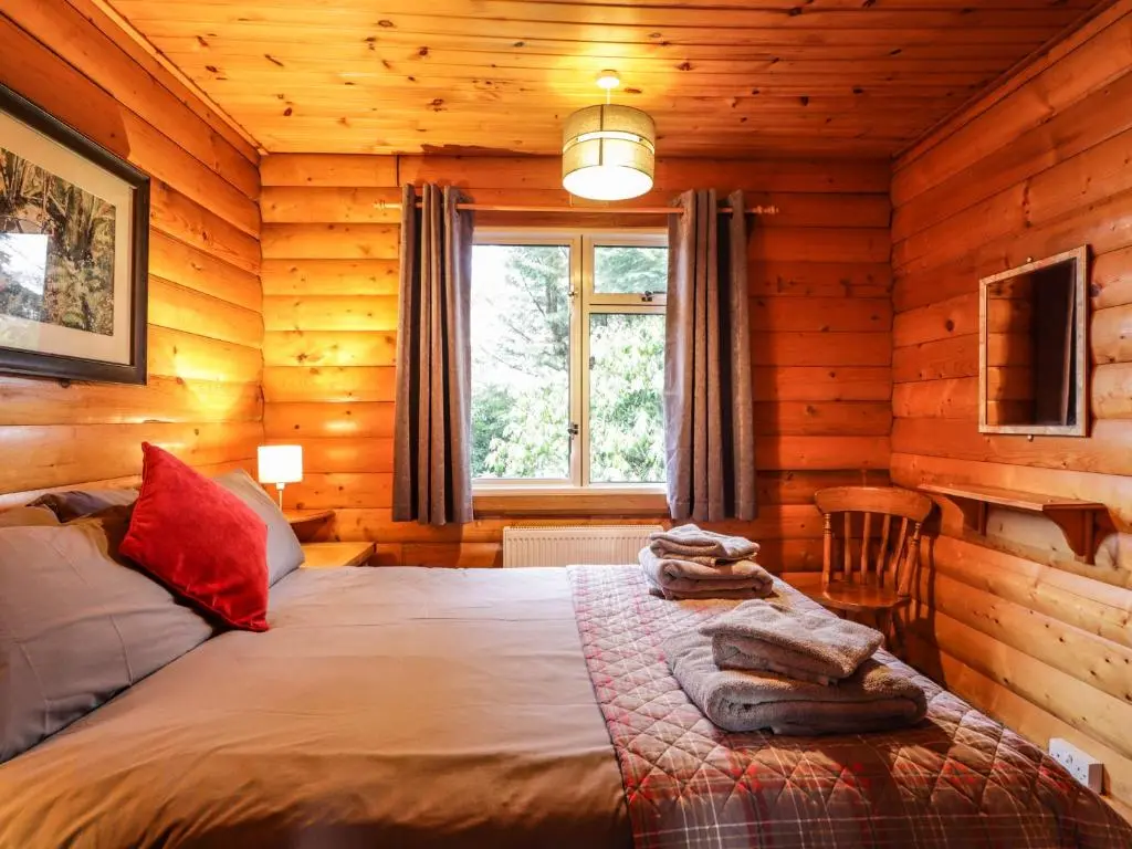 a bedroom with a bed in a log cabin at Rowan Lodge in Strathpeffer