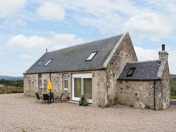 a small stone house with a table and chairs outside at The Auld Kirk in Forsinain