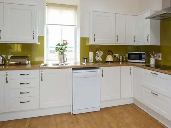 a white kitchen with white cabinets and a window at The Auld Kirk in Forsinain