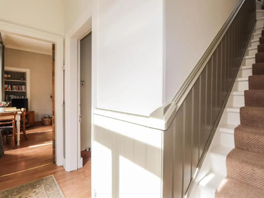 a staircase in a home with white walls and wood floors at Aultmore in Kingussie