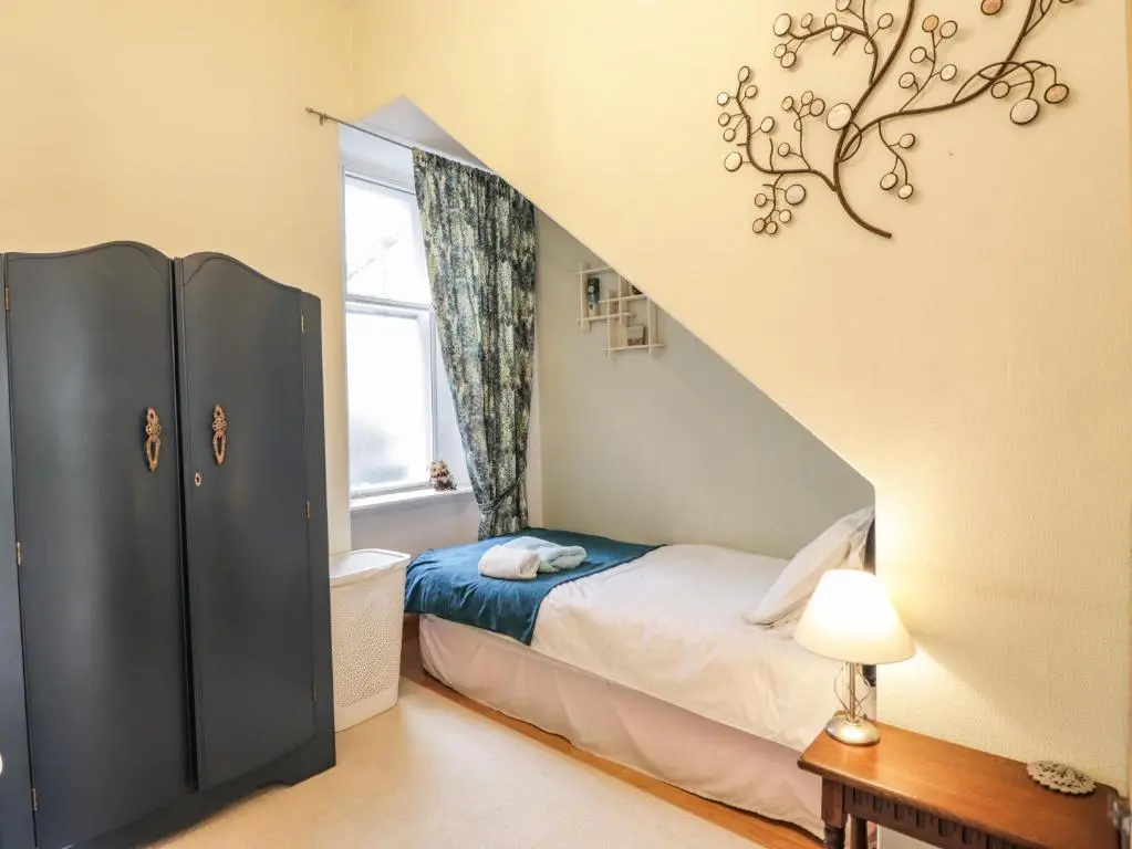 a small bedroom with a bed and a staircase at Aultmore in Kingussie