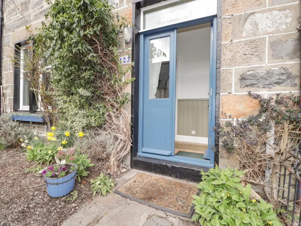 a blue door on a brick building with plants at Aultmore in Kingussie