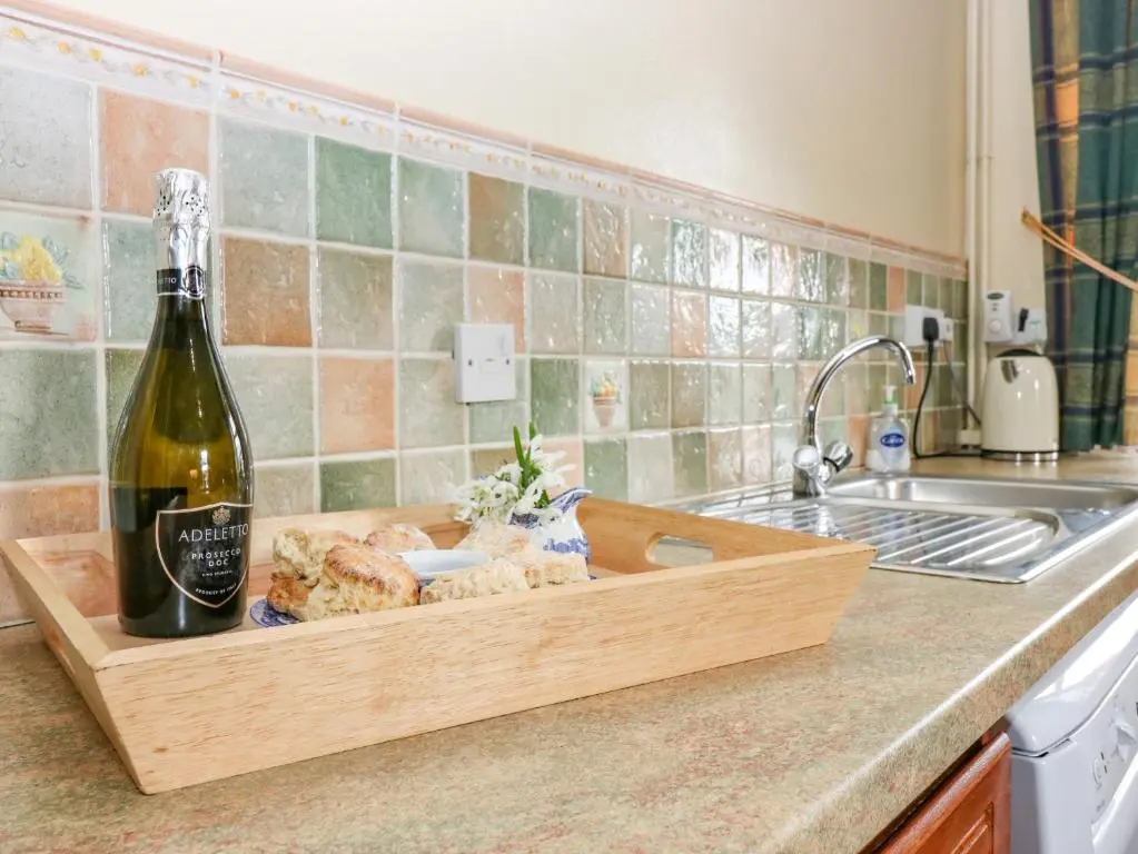 a bottle of wine and bread in a wooden tray on a kitchen counter at The West Wing in Skye of Curr