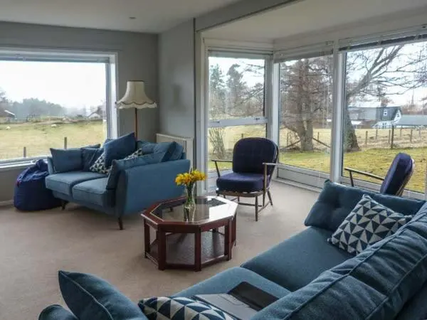 a living room with blue couches and a table at Fronthill in Newtonmore