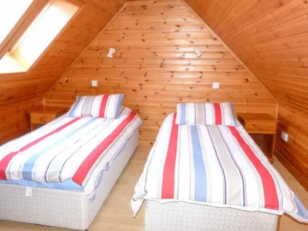 two beds in a attic room with wooden walls at Strathavon Chalet in Aviemore