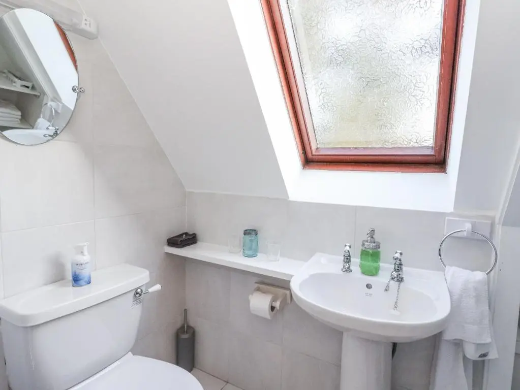 a bathroom with a toilet and a sink and a window at Deskford Cottage in Balblair