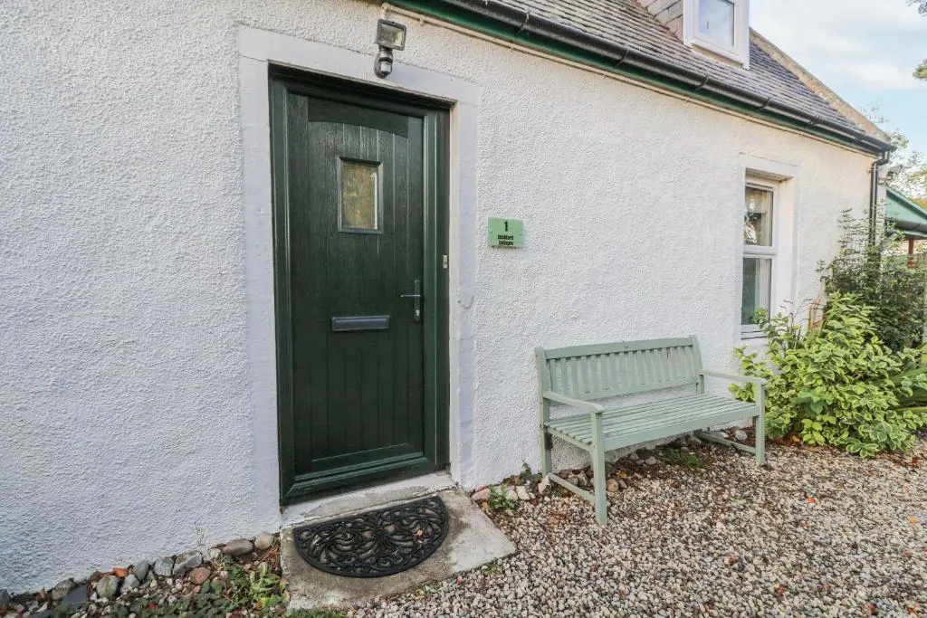 a green door and a bench in front of a house at Deskford Cottage in Balblair