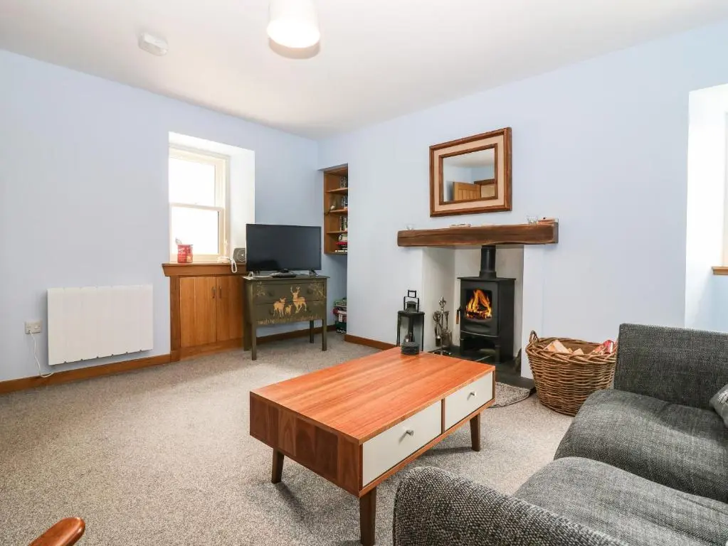 a living room with a coffee table and a fireplace at 49 Crovie Village in Gardenstown