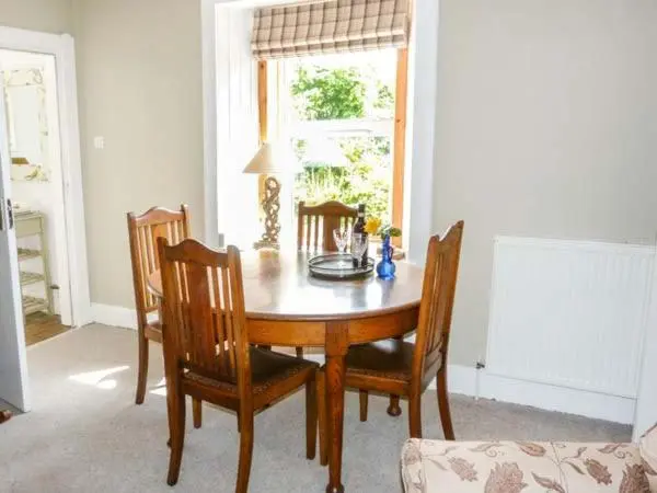 a dining room table with four chairs and a window at Coorie Doon in Nairn