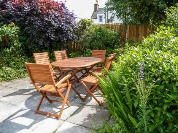 a wooden table and chairs in a garden at Coorie Doon in Nairn