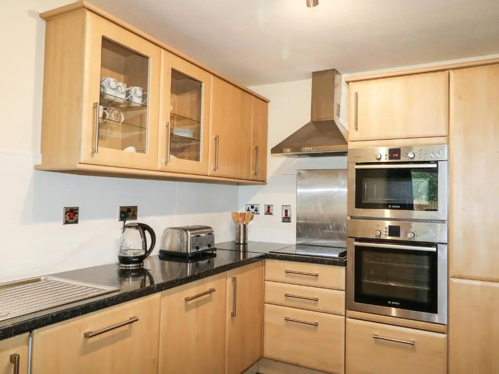 a kitchen with wooden cabinets and stainless steel appliances at 79 Corrour Road in Aviemore