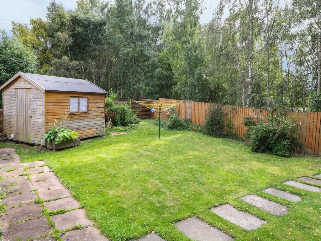a backyard with a wooden shed and a fence at 79 Corrour Road in Aviemore