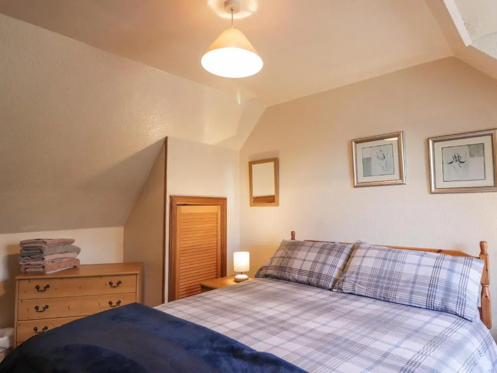 a bedroom with a bed and a dresser and a lamp at Alt na Voir in Tomintoul