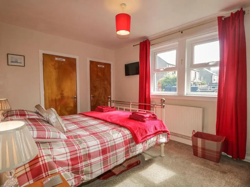 a bedroom with a bed with red curtains at Fishermans Rest in Burghead