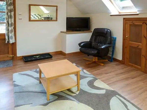 a living room with a black chair and a table at Lakefield Apartment in Bearnock