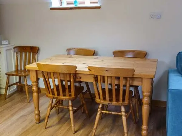 a wooden table with four chairs around it at Lakefield Apartment in Bearnock