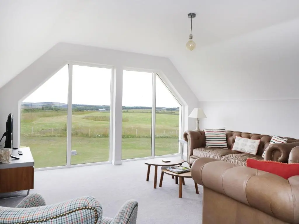 a living room with a couch and a large window at Chance Inn Lodge in Balmedie