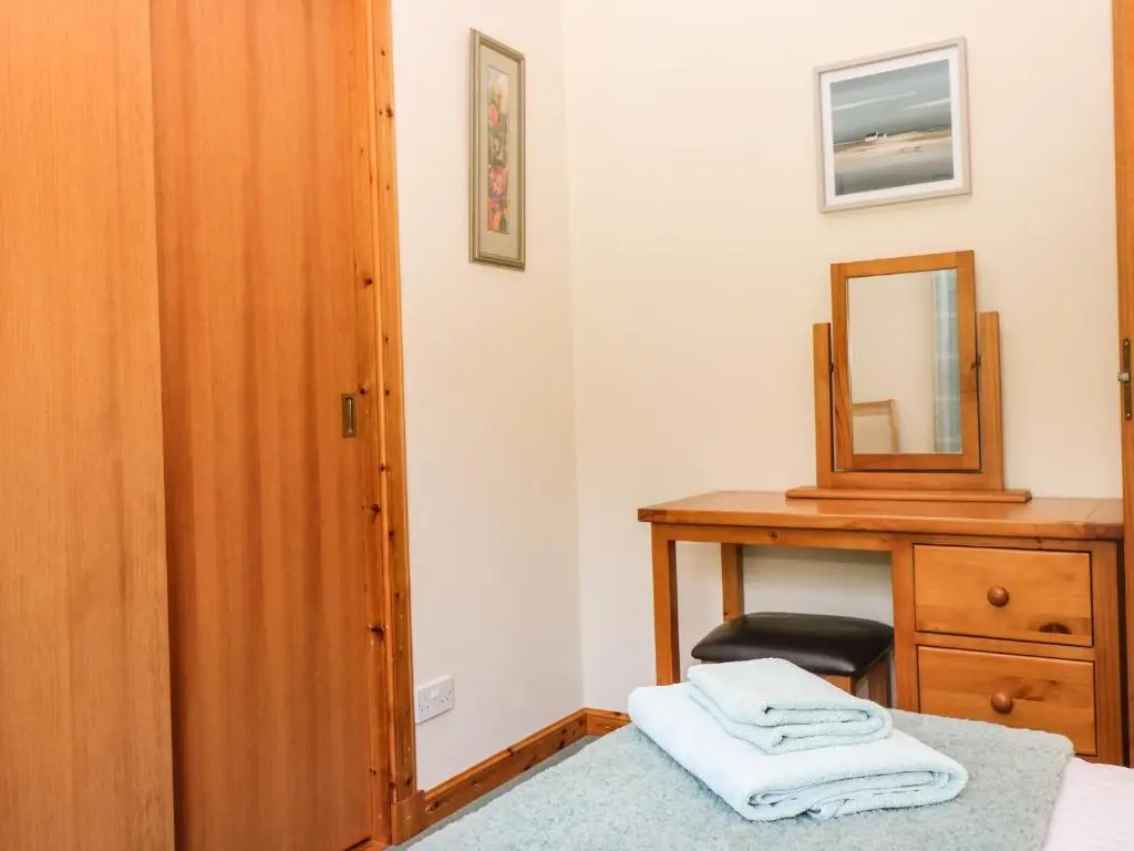 a bedroom with a wooden dresser and a mirror at Birchbank in Skye of Curr