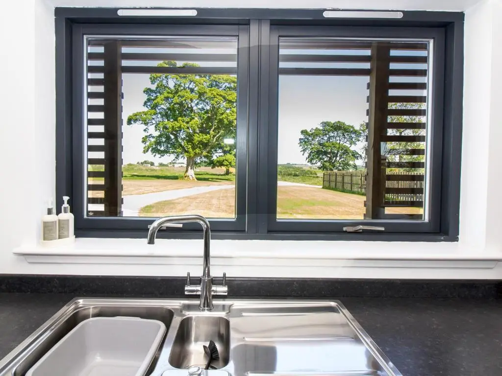 a kitchen with a sink and two windows at Nef-Stedi in Kirktown of Bourtie