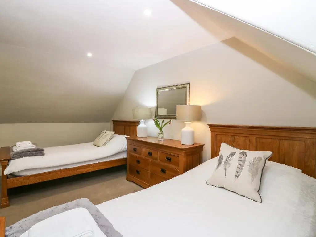 a attic bedroom with two beds and a tv at White Hillocks Farm House in Inchmill